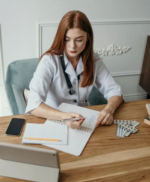 An administrative medical assistant makes notes and records data in a notebook.