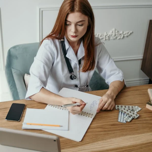 An administrative medical assistant makes notes and records data in a notebook.