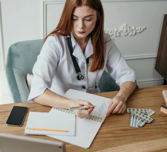 An administrative medical assistant makes notes and records data in a notebook.