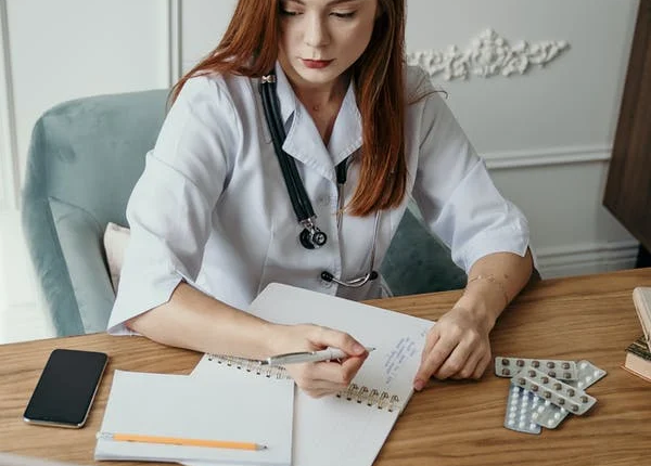 An administrative medical assistant makes notes and records data in a notebook.