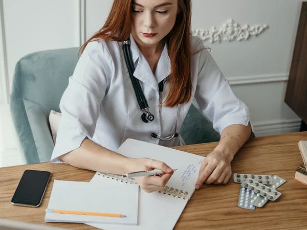 An administrative medical assistant makes notes and records data in a notebook.