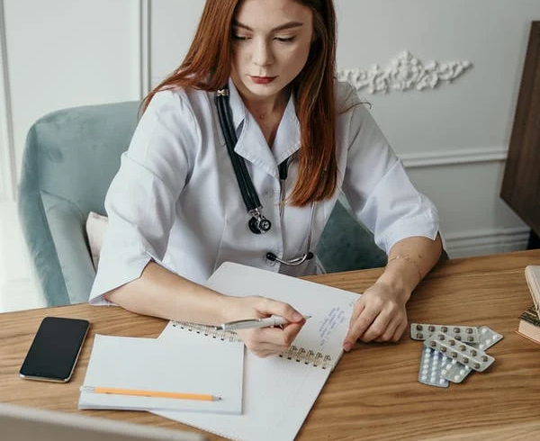 An administrative medical assistant makes notes and records data in a notebook.