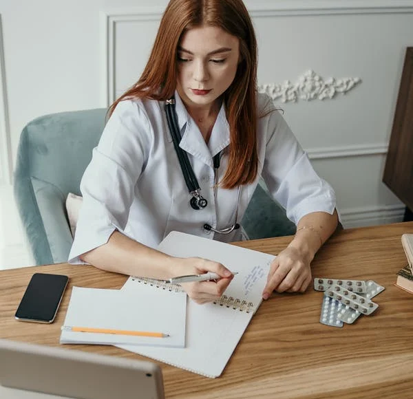 An administrative medical assistant makes notes and records data in a notebook.