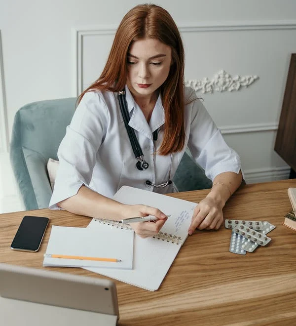 An administrative medical assistant makes notes and records data in a notebook.