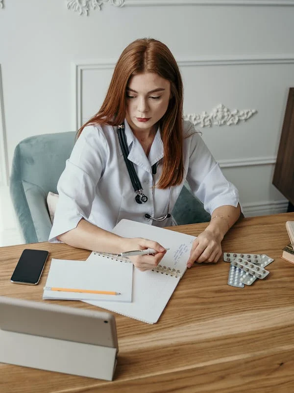 An administrative medical assistant makes notes and records data in a notebook.