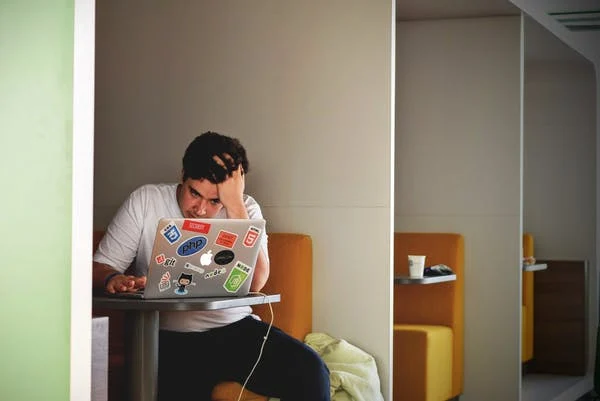  A young man looks stressed out as he works at his desk.
