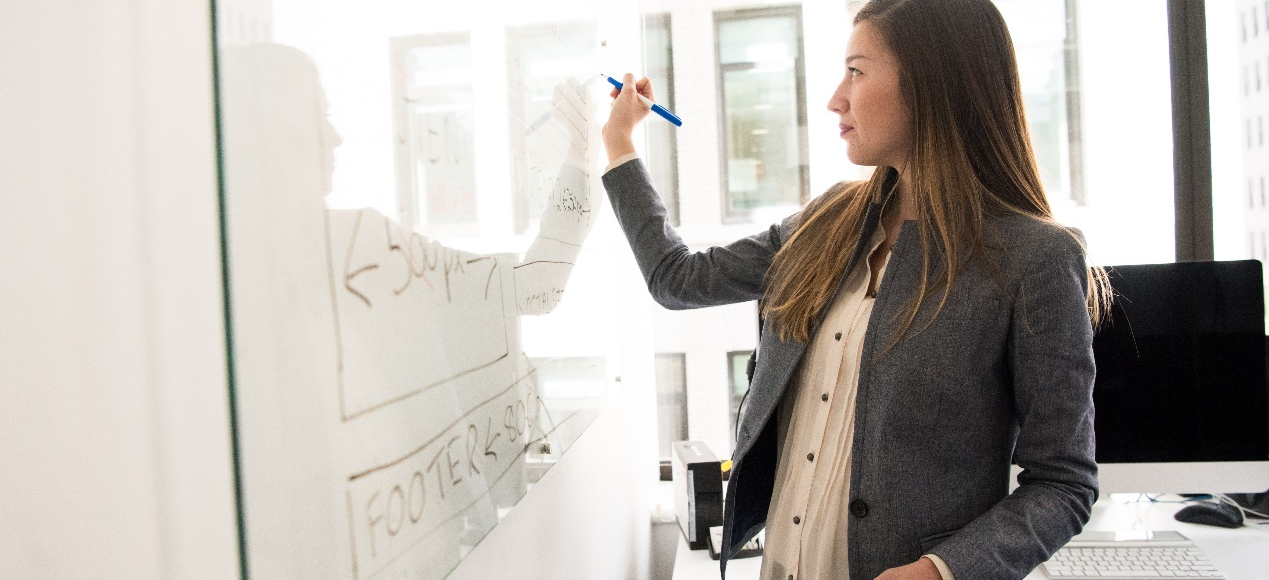 A woman writing on a board with a marker