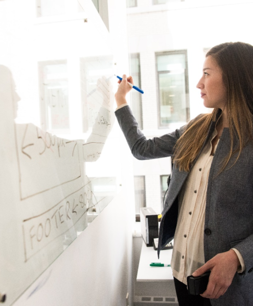 A woman writing on a board with a marker