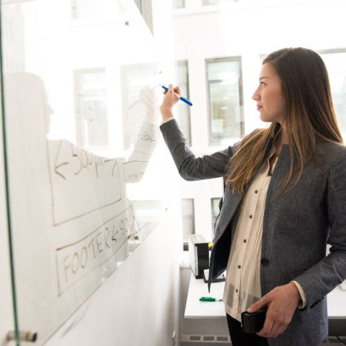 A woman writing on a board with a marker