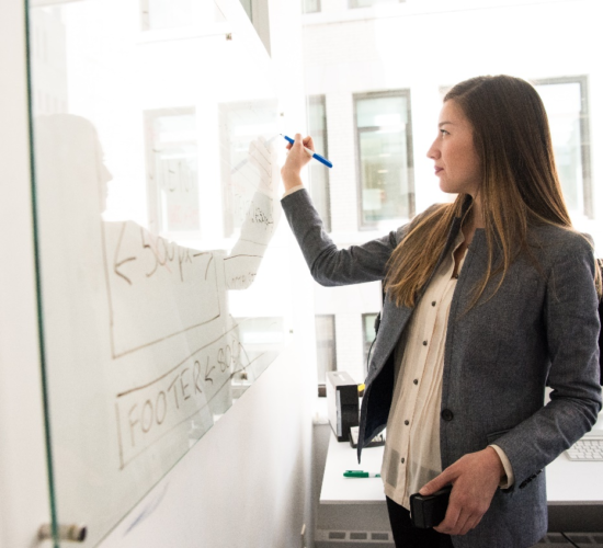 A woman writing on a board with a marker