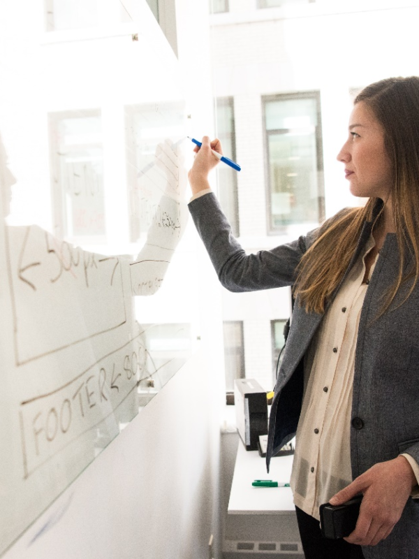 A woman writing on a board with a marker