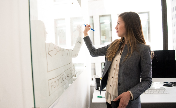 A woman writing on a board with a marker