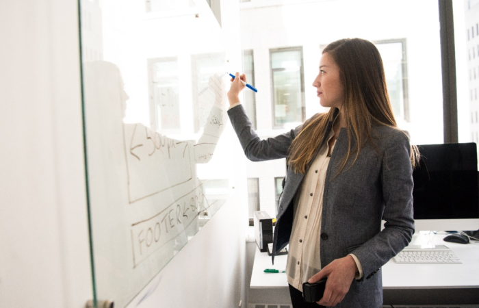 A woman writing on a board with a marker