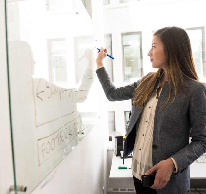 A woman writing on a board with a marker