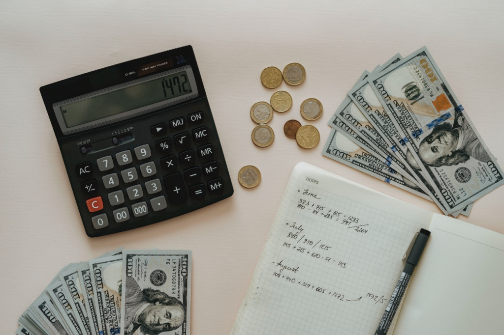 A calculator, money, and notebook on a desk