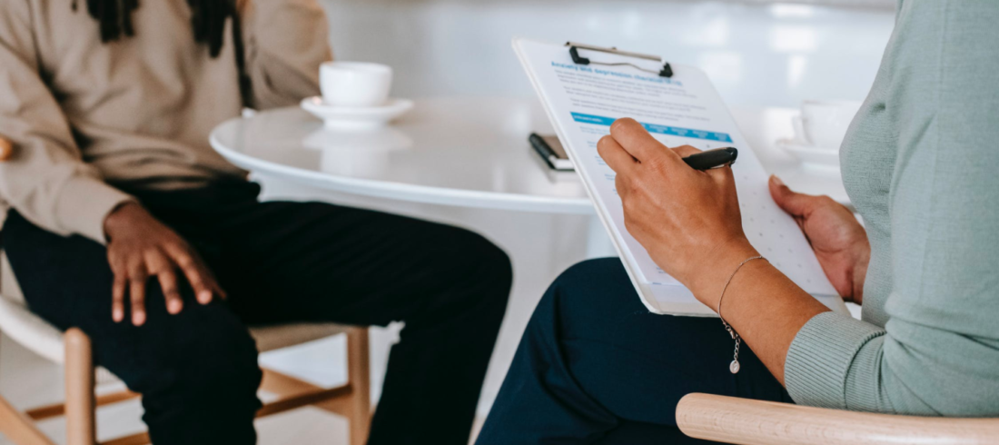 A career counselor helps their client, taking notes on their clipboard.