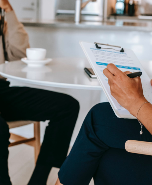 A career counselor helps their client, taking notes on their clipboard.