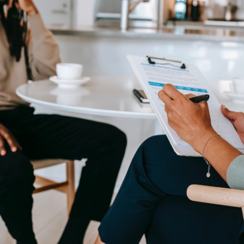 A career counselor helps their client, taking notes on their clipboard.