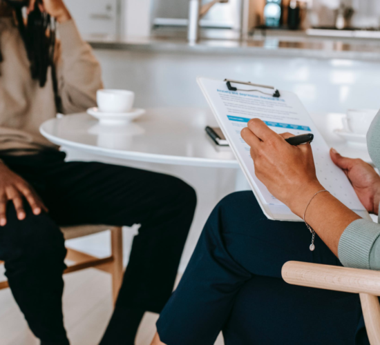 A career counselor helps their client, taking notes on their clipboard.