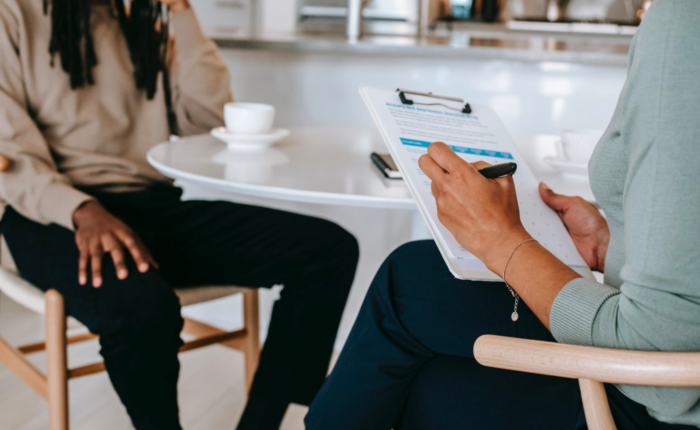 A career counselor helps their client, taking notes on their clipboard.