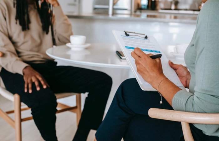 A career counselor helps their client, taking notes on their clipboard.