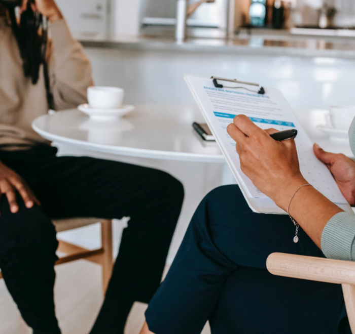 A career counselor helps their client, taking notes on their clipboard.