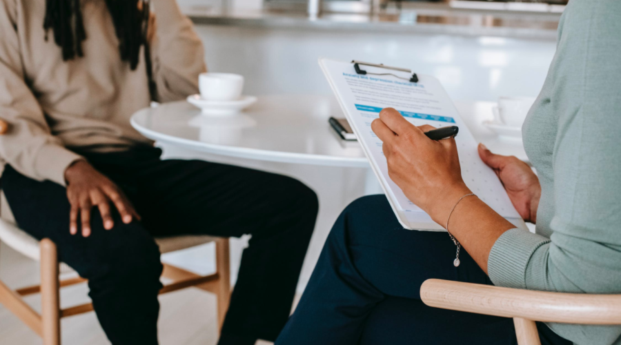 A career counselor helps their client, taking notes on their clipboard.