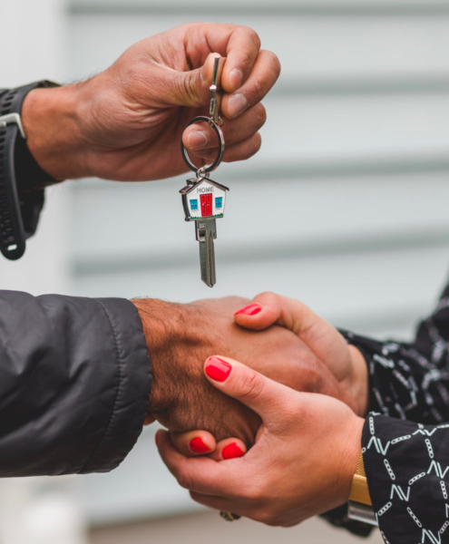 A real estate agent shakes hands with a client who holds a key after a successful closing.