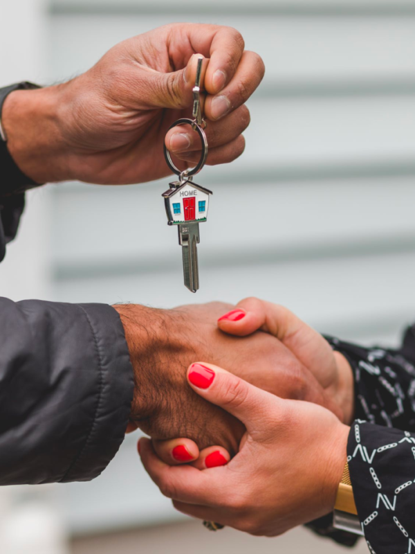 A real estate agent shakes hands with a client who holds a key after a successful closing.