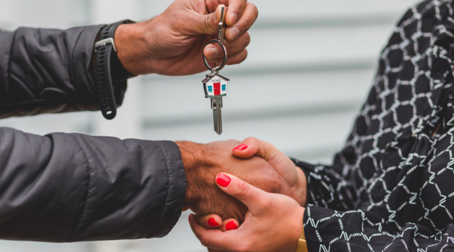 A real estate agent shakes hands with a client who holds a key after a successful closing.