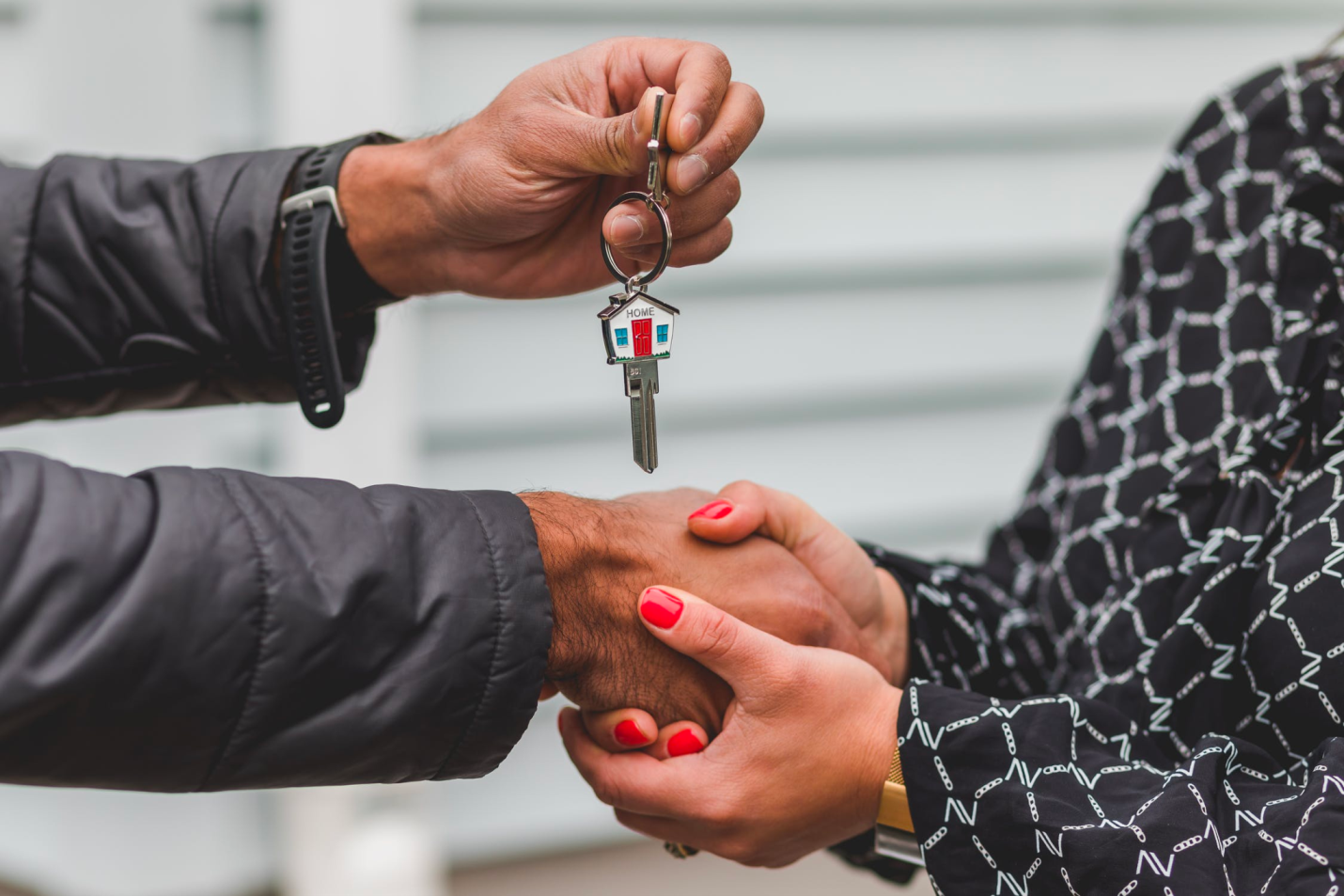 A real estate agent shakes hands with a client who holds a key after a successful closing.