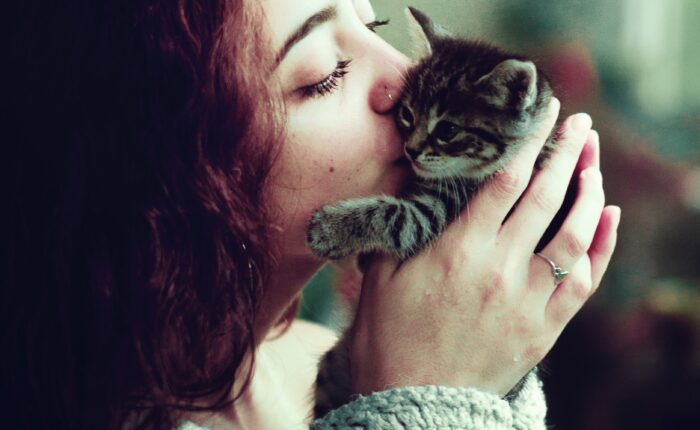 woman kissing a small kitten