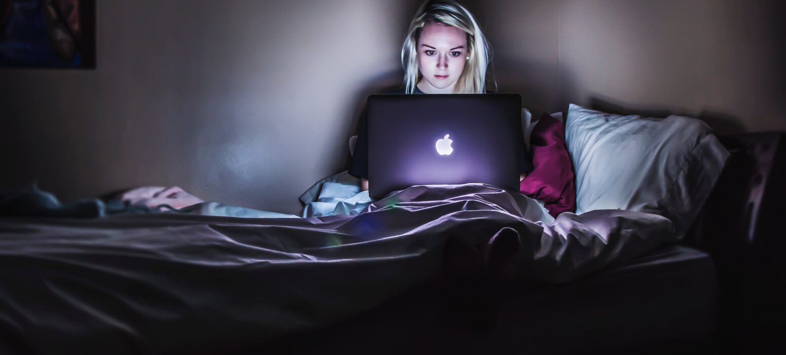 woman earning her online degree from her bed