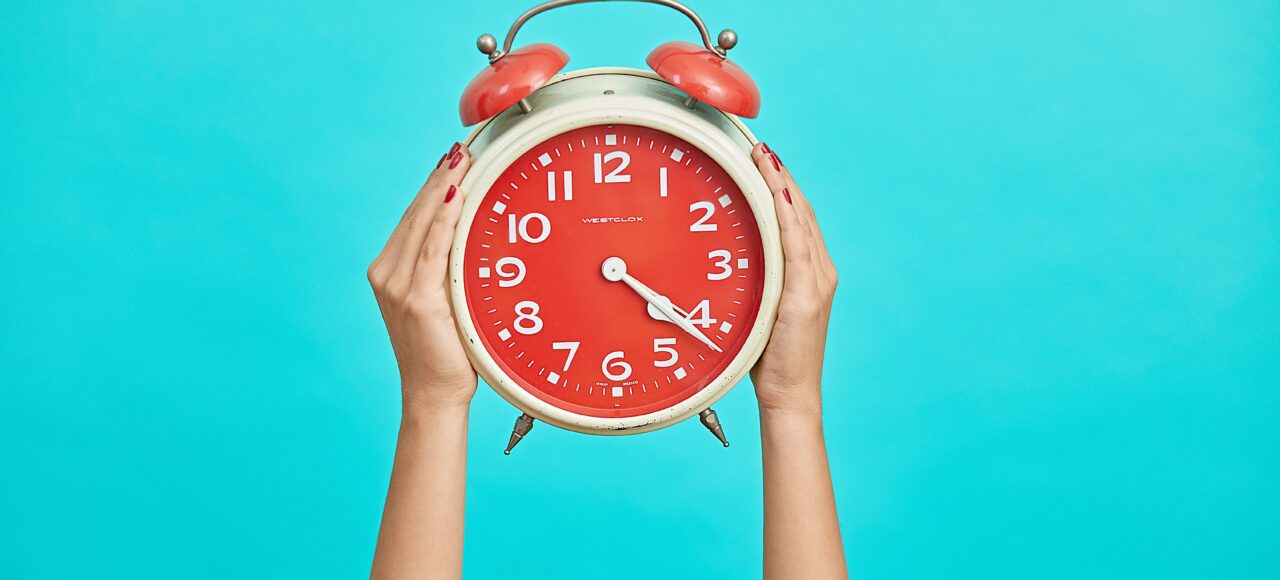 red alarm clock over a blue background