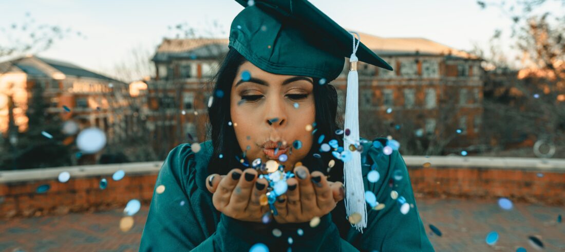 graduate blowing confetti