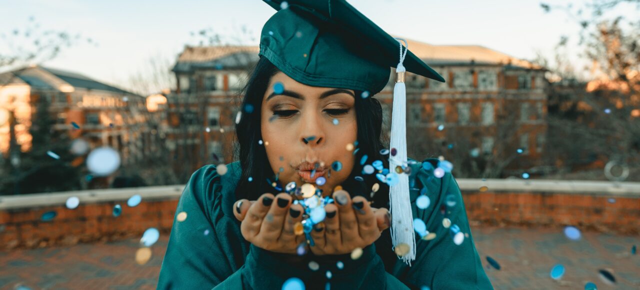 graduate blowing confetti