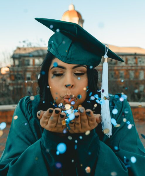 graduate blowing confetti