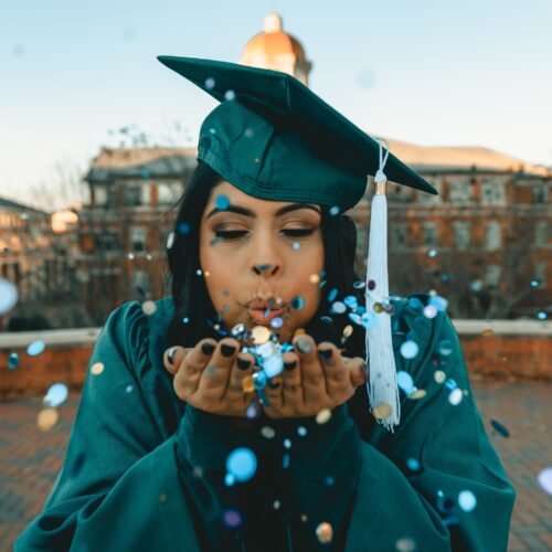 graduate blowing confetti