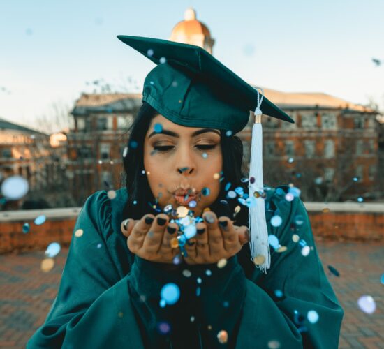 graduate blowing confetti