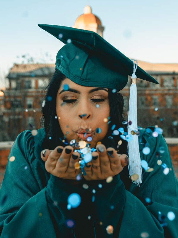 graduate blowing confetti