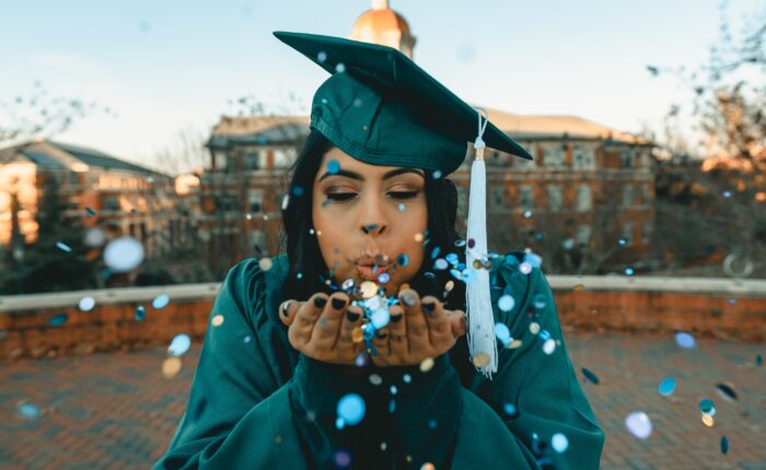 graduate blowing confetti