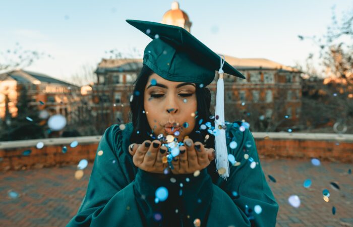 graduate blowing confetti