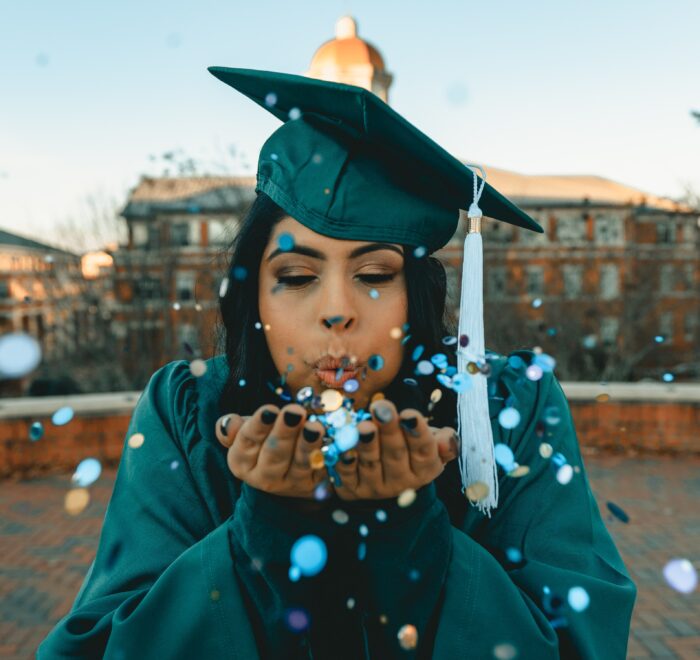 graduate blowing confetti