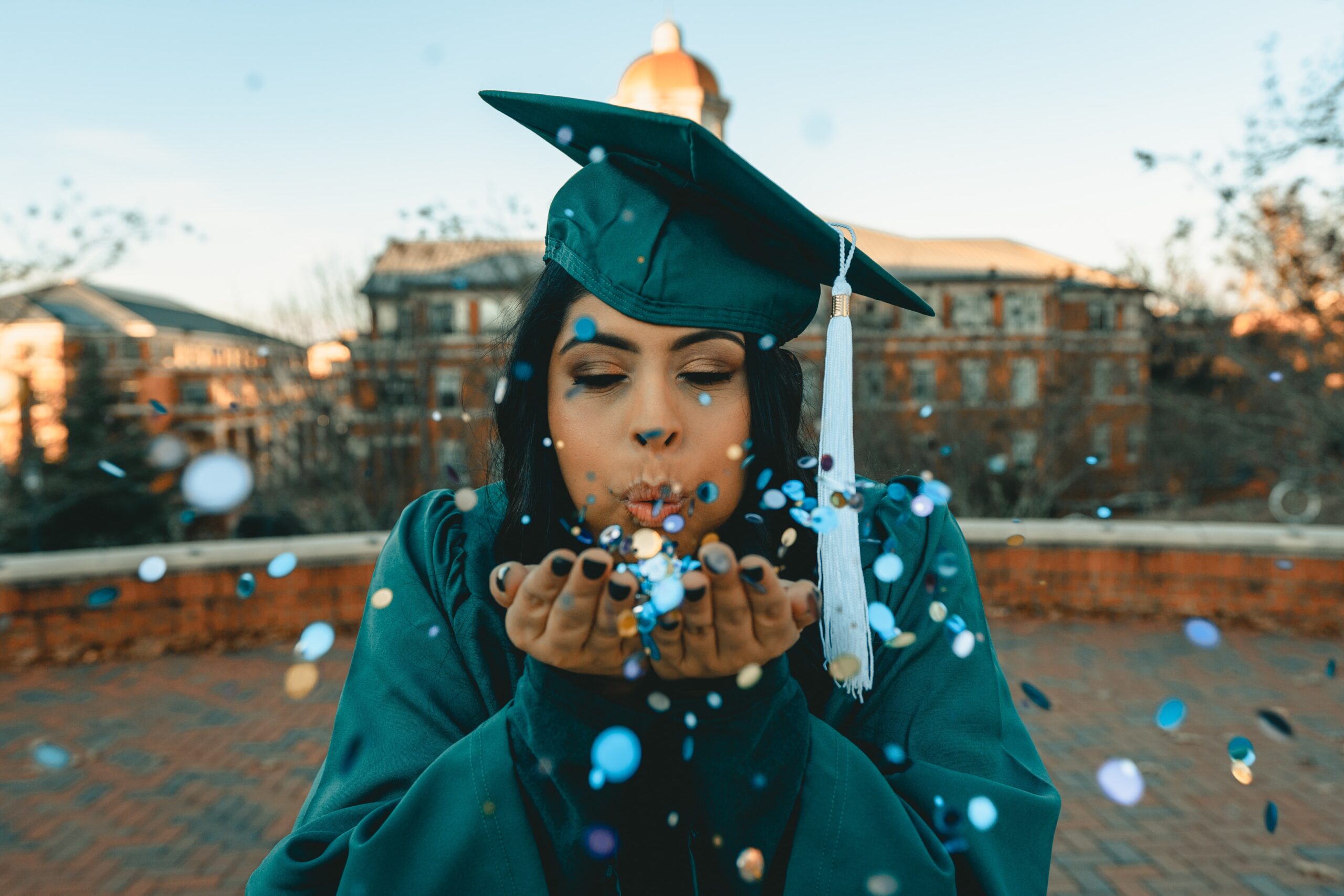 graduate blowing confetti