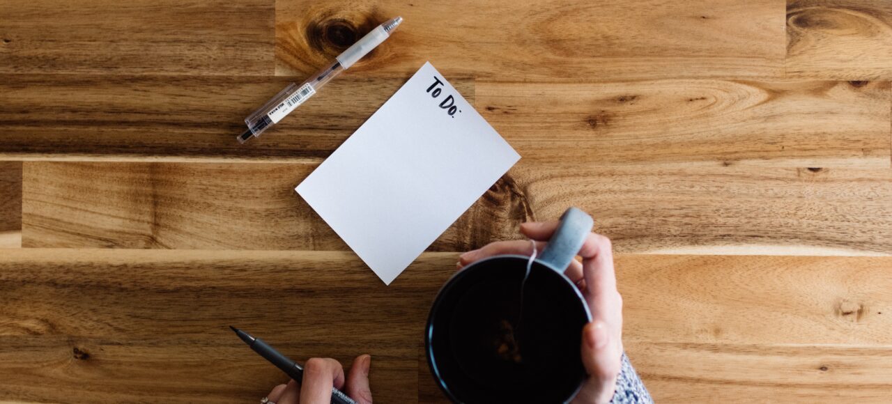 woman with a coffee mug and a to-do list learning how to prioritize