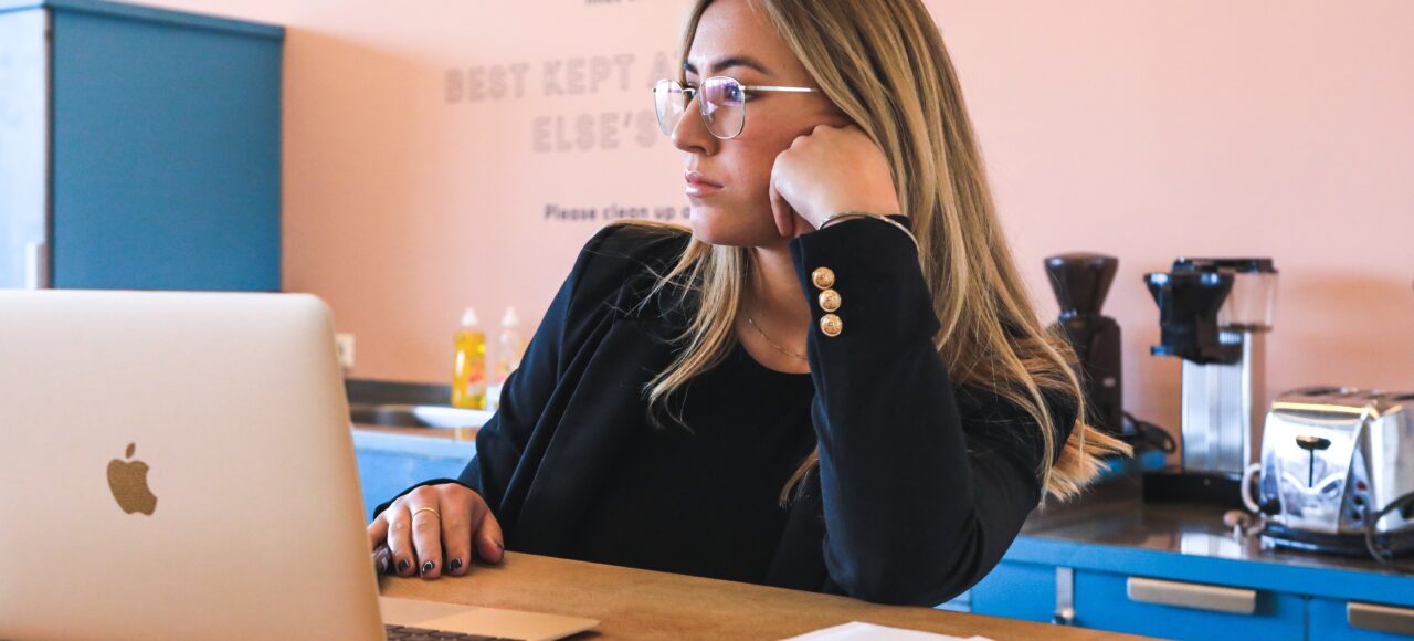 woman in a toxic workplace, bored at laptop