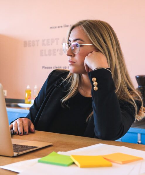 woman in a toxic workplace, bored at laptop