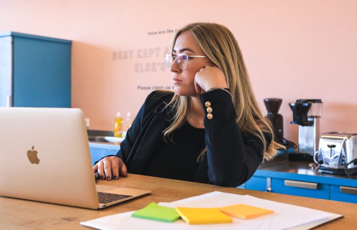 woman in a toxic workplace, bored at laptop