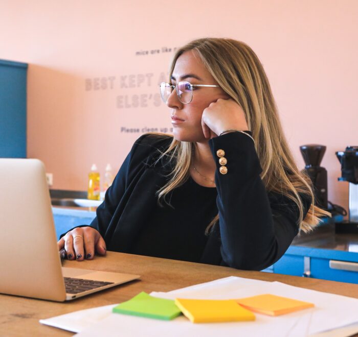 woman in a toxic workplace, bored at laptop