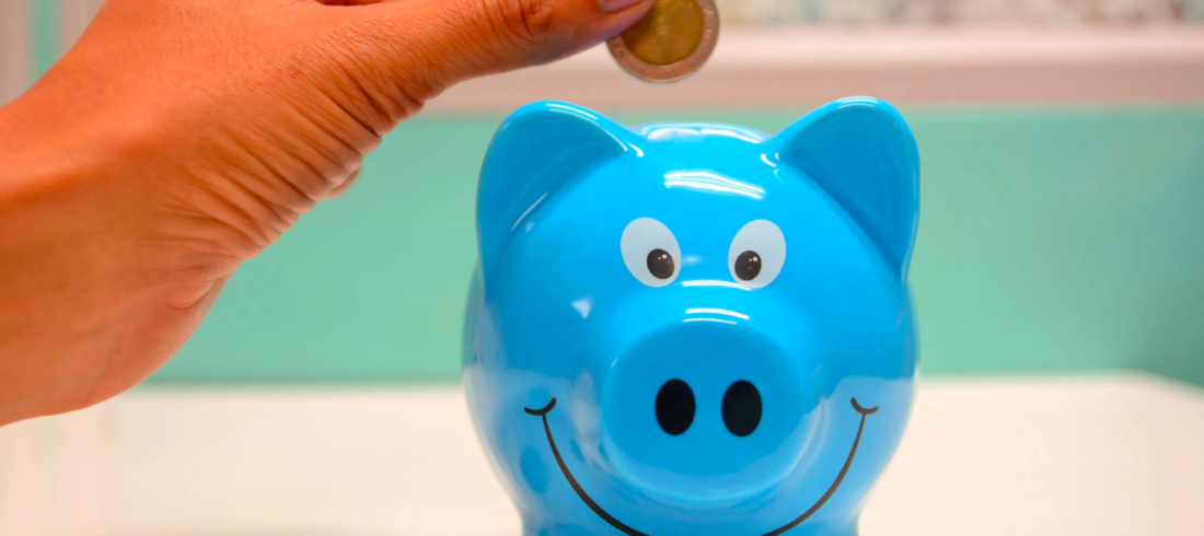 A person inserts coins into a piggy bank to save